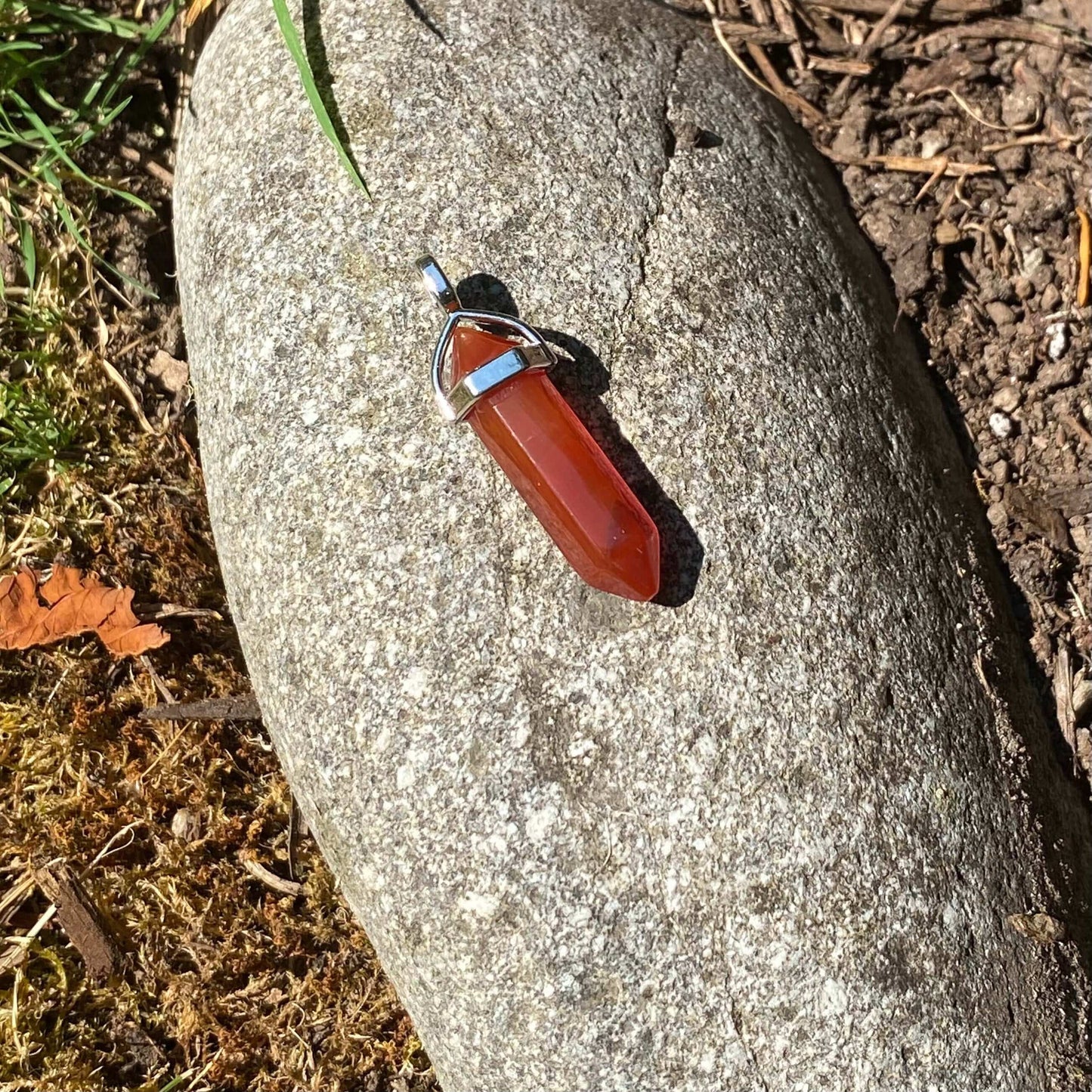 Carnelian Point Pendant-Gemstone Jewelry This stylish crystal pendant features a double terminated polished carnelian point in a metal cap. It comes with a black cord necklace. *Chain sold separately. Approx. 45 mm length x 7mm width Packaging: This penda
